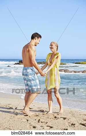 Couple holding hands on beach View Large Photo Image Picture - Couple holding hands on beach. Fotosearch