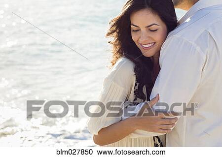 Stock Image - Couple hugging on beach. Fotosearch