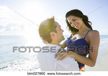 Stock Image - Couple hugging on beach. Fotosearch