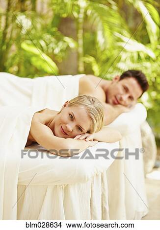 Picture - Couple laying on massage tables outdoors. Fotosearch