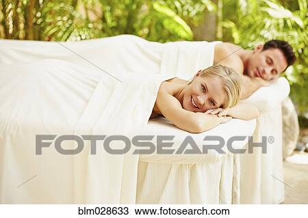 Stock Image - Couple laying on massage tables outdoors. Fotosearch