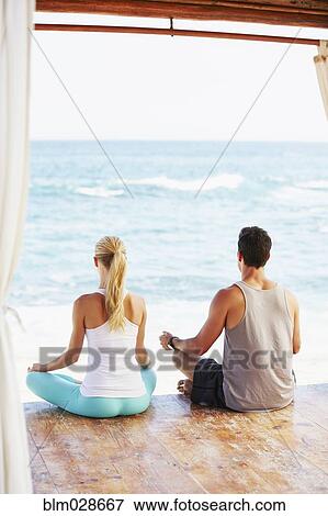Couple meditating together in cabana overlooking ocean View Large Photo Image Stock Photo - Couple meditating together in cabana overlooking ocean. Fotosearch