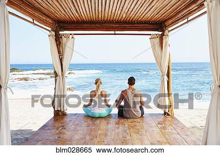Couple meditating together in cabana overlooking ocean View Large Photo Image Stock Photography - Couple meditating together in cabana overlooking ocean. Fotosearch