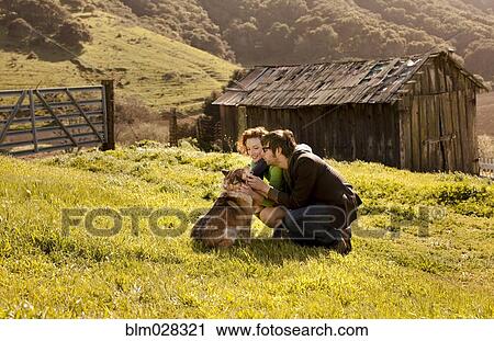 Couple petting dog in rural landscape View Large Photo Image Stock Image - Couple petting dog in rural landscape. Fotosearch