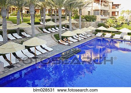 Stock Image - Couple relaxing by swimming pool. Fotosearch