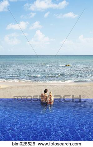 Couple relaxing in infinity pool View Large Photo Image Stock Photograph - Couple relaxing in infinity pool. Fotosearch
