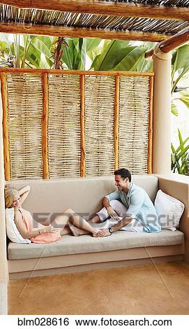 Couple relaxing together on patio sofa View Large Photo Image Stock Photograph - Couple relaxing together on patio sofa. Fotosearch