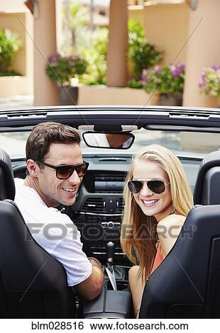Stock Photograph - Couple sitting in convertible outdoors. Fotosearch