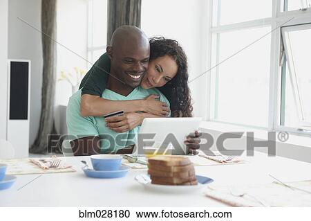 Couple with digital tablet hugging at breakfast table View Large Photo Image Stock Image - Couple with digital tablet hugging at breakfast table. Fotosearch