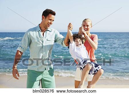 Stock Photograph - Family playing together on beach. Fotosearch