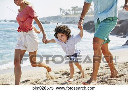Stock Photography - Family running together on beach. Fotosearch