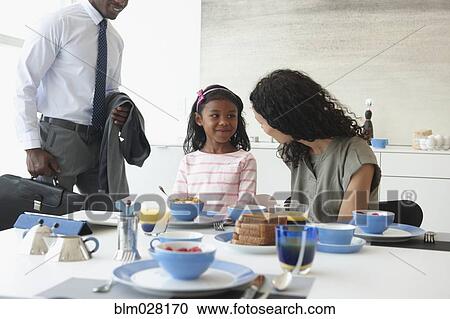 Stock Image - Family talking at breakfast table. Fotosearch