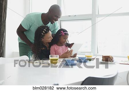 Stock Image - Family with digital tablet at breakfast table. Fotosearch