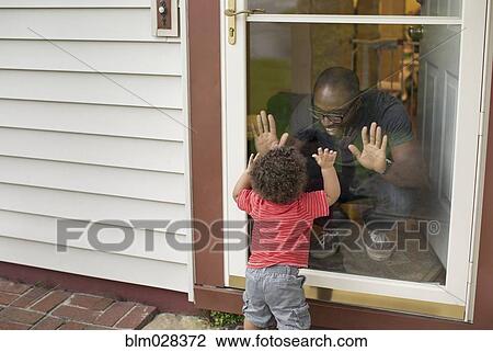 Stock Image - Father and toddler son playing at screen door. Fotosearch