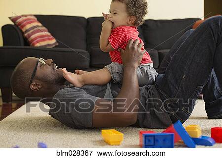 Stock Photo - Father and toddler son playing in living room. Fotosearch