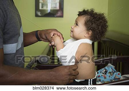Father changing toddler son's clothes in nursery View Large Photo Image Picture - Father changing toddler son's clothes in nursery. Fotosearch