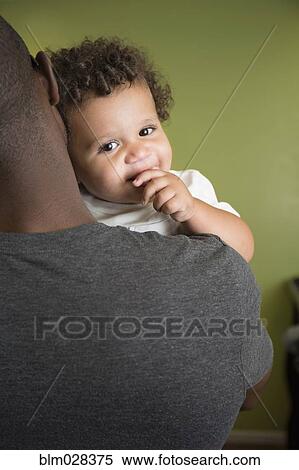 Stock Photography - Father holding toddler son in bedroom. Fotosearch