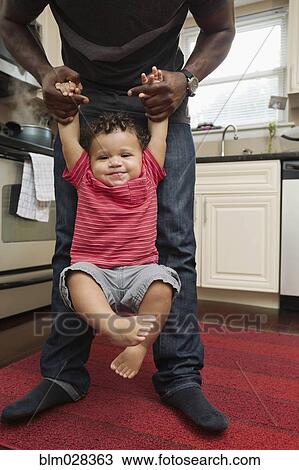 Father holding toddler son in kitchen View Large Photo Image Stock Image - Father holding toddler son in kitchen. Fotosearch