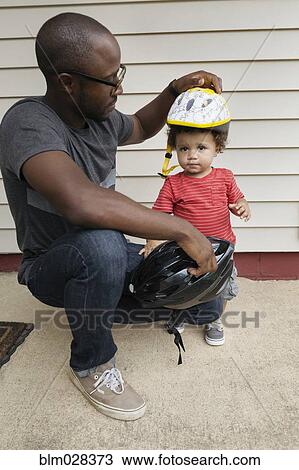 Father putting helmet on toddler son View Large Photo Image Stock Image - Father putting helmet on toddler son. Fotosearch