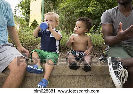 Fathers and toddler sons sitting together in park View Large Photo Image Stock Image - Fathers and toddler sons sitting together in park. Fotosearch