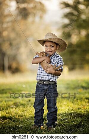 Stock Image - Hispanic boy holding puppy outdoors. Fotosearch