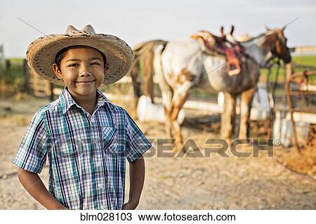 Stock Image - Hispanic boy smiling on ranch. Fotosearch