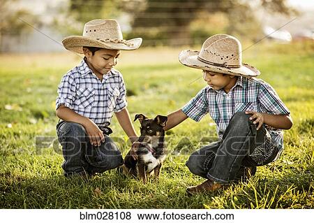 Stock Photo - Hispanic boys petting dog outdoors. Fotosearch