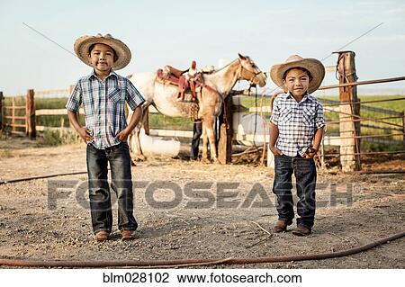 Stock Image - Hispanic boys smiling on ranch. Fotosearch