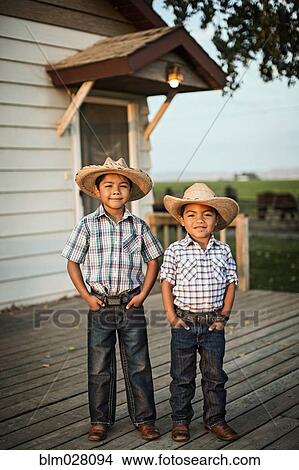 Picture - Hispanic boys wearing cowboy hats outdoors. Fotosearch
