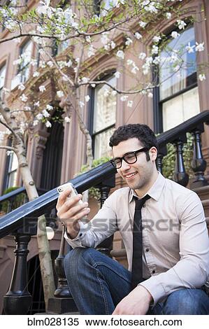 Hispanic businessman using cell phone on front steps View Large Photo Image Stock Photography - Hispanic businessman using cell phone on front steps. Fotosearch
