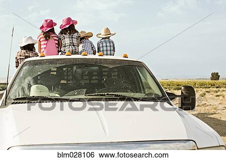 Stock Photograph - Hispanic family sitting in bed of truck. Fotosearch