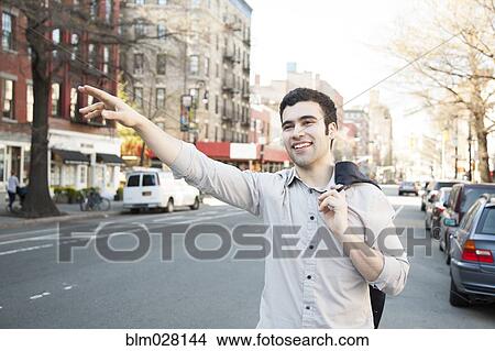 Picture - Hispanic man hailing taxi on city street. Fotosearch