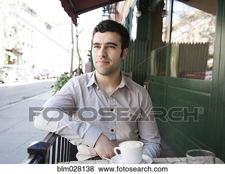 Stock Photo - Hispanic man sitting at sidewalk cafe. Fotosearch