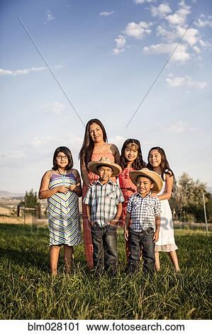 Stock Image - Hispanic mother and children smiling outside house. Fotosearch