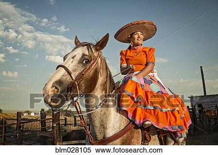 Stock Photography - Hispanic woman in traditional dress on horse. Fotosearch