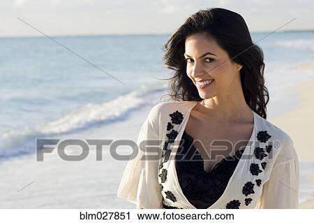 Stock Image - Hispanic woman smiling on beach. Fotosearch