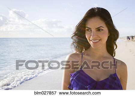 Stock Photo - Hispanic woman walking on beach. Fotosearch