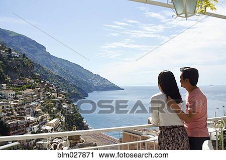 Stock Image - Korean couple overlooking hillside city, Positano, Campania, Italy. Fotosearch