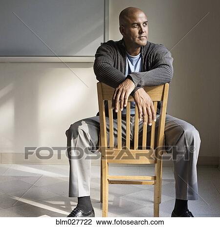 Stock Image - Man sitting in wooden chair. Fotosearch