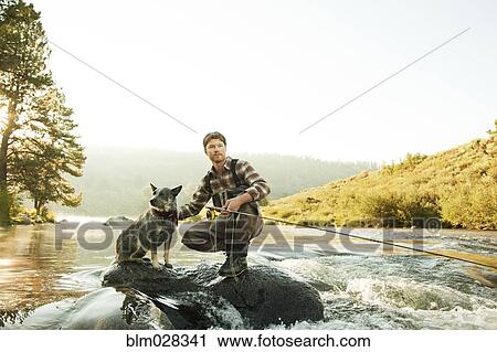 Man with dog fishing in river View Large Photo Image Stock Image - Man with dog fishing in river. Fotosearch
