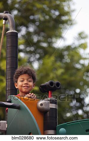 Stock Image - Mixed race boy climbing playground structure. Fotosearch