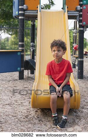 Mixed race boy sitting on playground slide View Large Photo Image Stock Image - Mixed race boy sitting on playground slide. Fotosearch