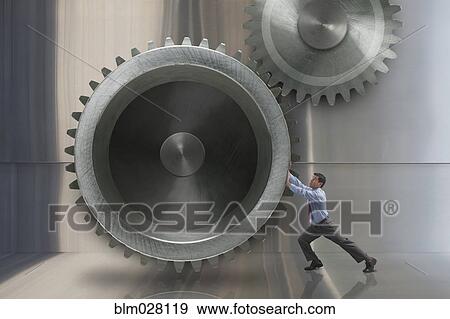 Mixed race businessman turning large metal gears View Large Photo Image Stock Photo - Mixed race businessman turning large metal gears. Fotosearch