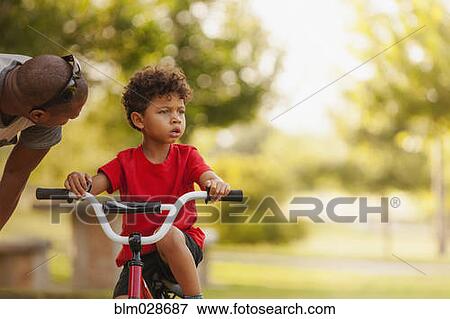 Mixed race father and son relaxing in park View Large Photo Image Stock Photo - Mixed race father and son relaxing in park. Fotosearch