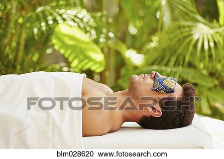 Stock Image - Mixed race man laying on massage table. Fotosearch