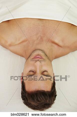 Stock Image - Mixed race man laying on massage table. Fotosearch