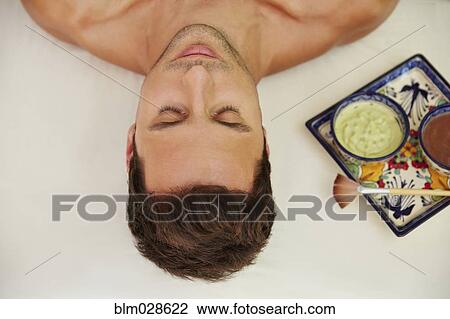 Stock Image - Mixed race man laying on massage table. Fotosearch