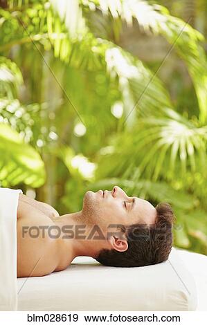 Stock Photo - Mixed race man laying on massage table. Fotosearch
