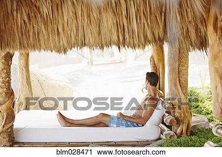 Mixed race man relaxing in cabana View Large Photo Image Stock Image - Mixed race man relaxing in cabana. Fotosearch