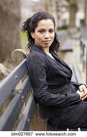 Stock Photo - Mixed race woman sitting on park bench. Fotosearch